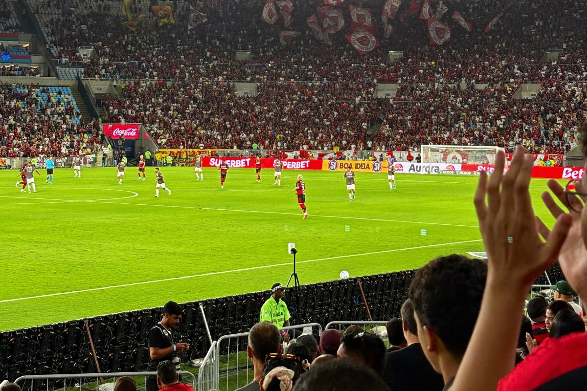 Vista do Setor Leste Inferior do Maracanã com jogadores do Flamengo em campo e torcida rubro-negra lotando a arquibancada ao fundo