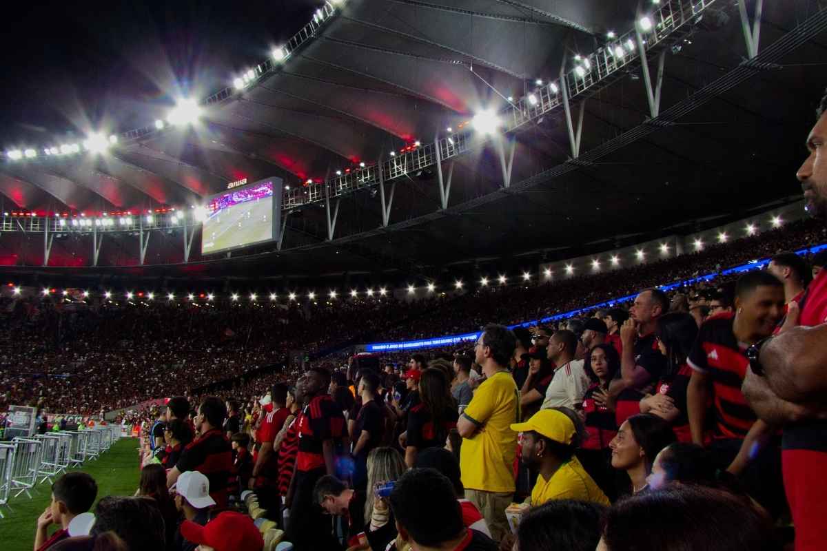 Maracanã iluminado em noite de jogo do Flamengo, com a torcida rubro-negra nas arquibancadas