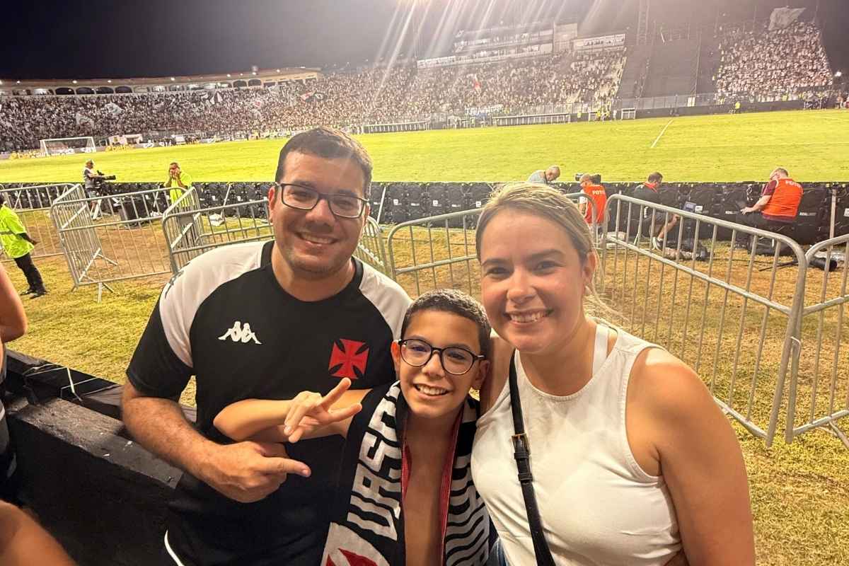 Família de torcedores do Vasco sorrindo na beira do gramado de São Januário em noite de jogo