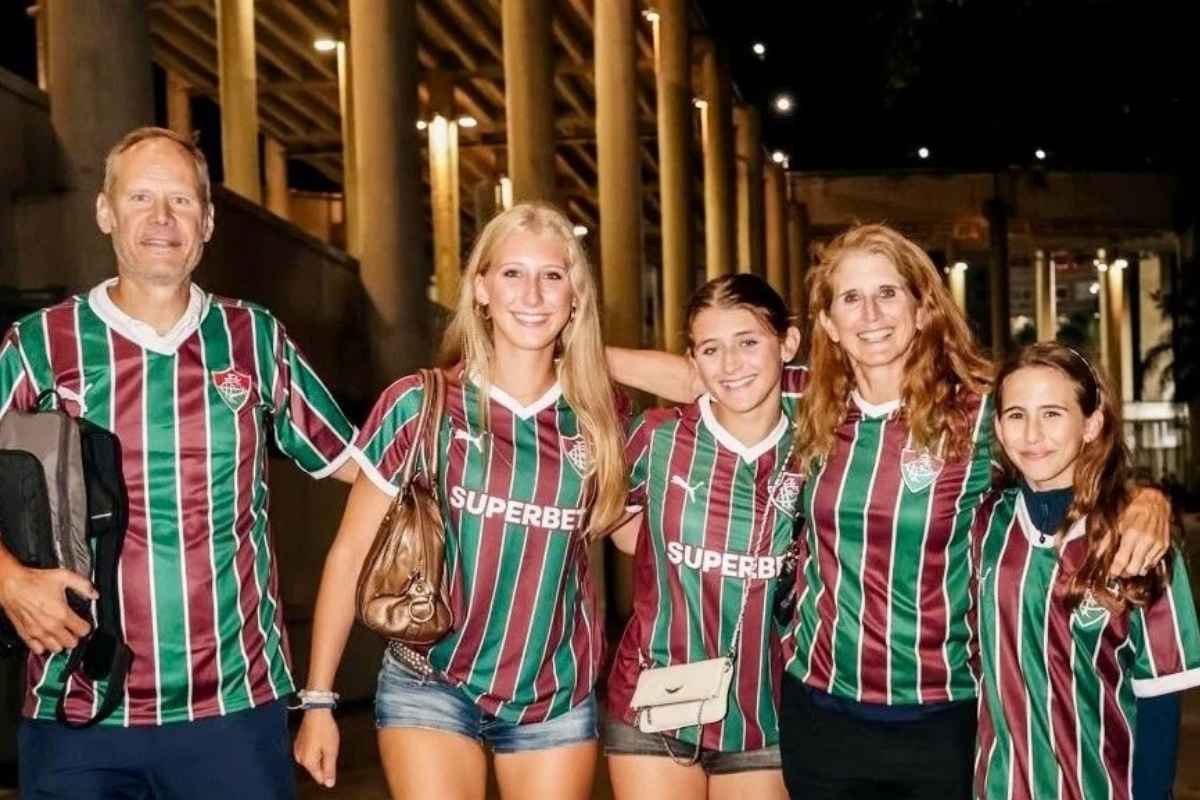 Família de torcedores com camisas do Fluminense posando no Maracanã em noite de jogo